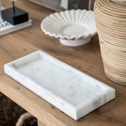 Bandeja de mármol blanco sobre consola de madera en ambiente decorativo.