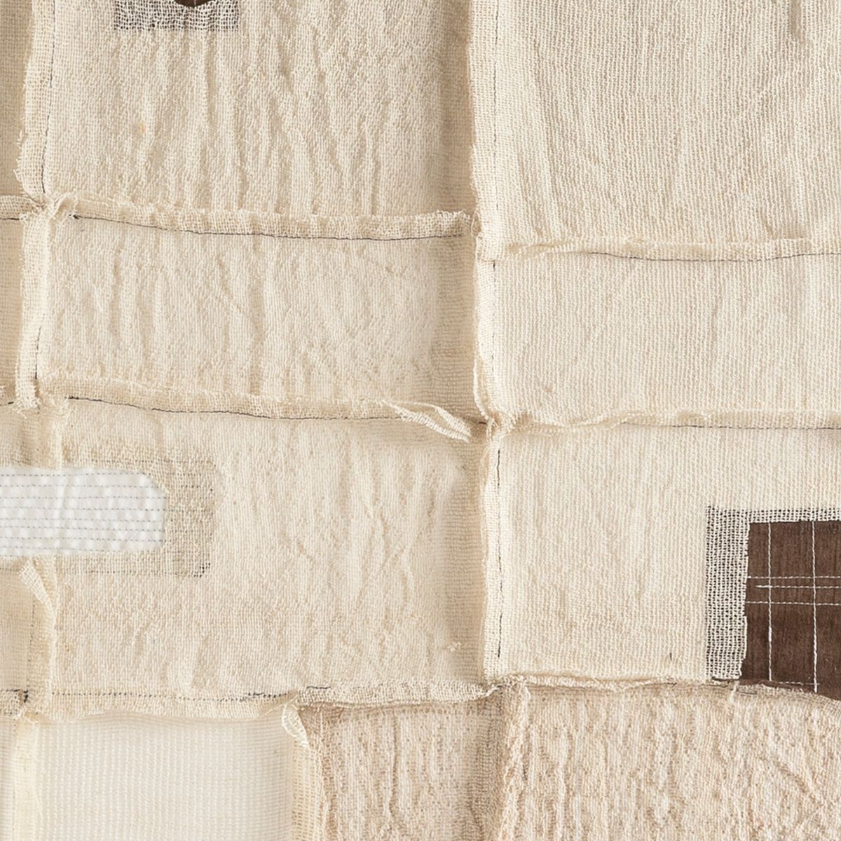 Detalle de cuadro textil con tejidos superpuestos en tonos beige, crudo y marrón
