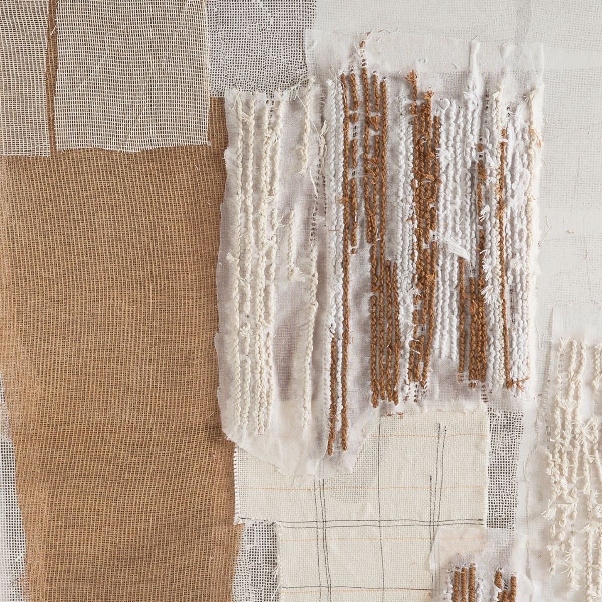 Detalle de cuadro textil con tejidos superpuestos y bordados en tonos beige, blanco y marrón