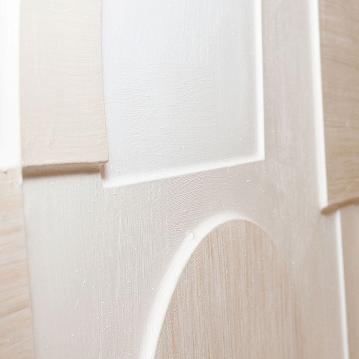 Detalle lateral de cuadro abstracto con formas geométricas en beige, blanco y madera clara