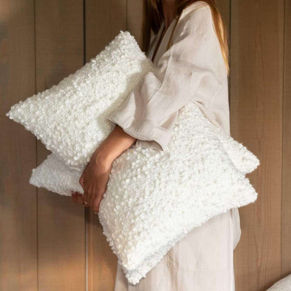Mujer sujetando cojines de bouclé blacos