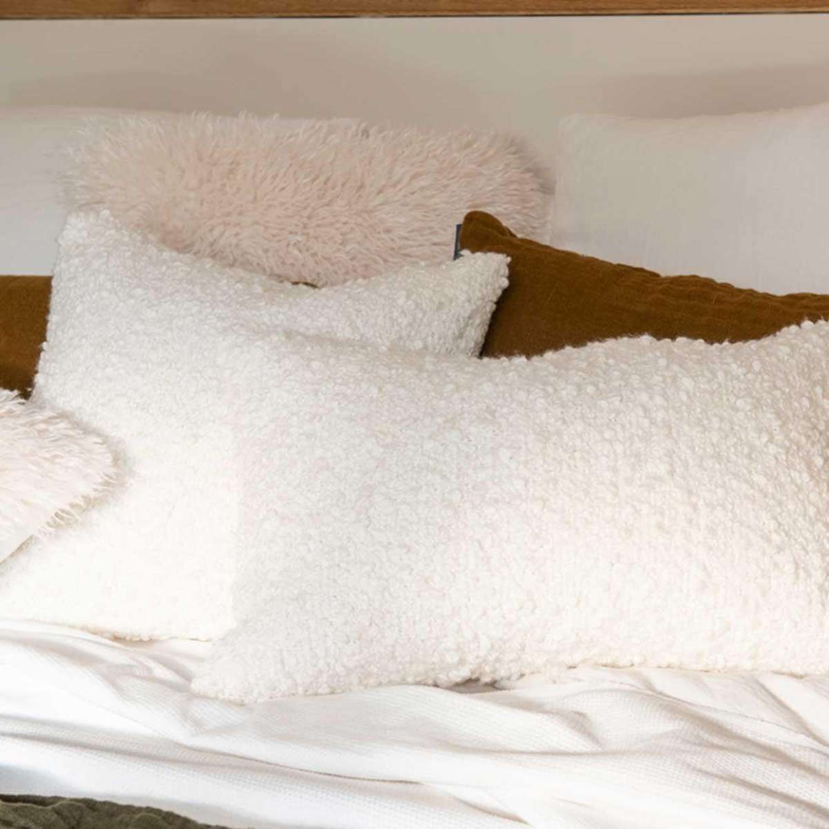 Cama con cojines de bouclé blancos