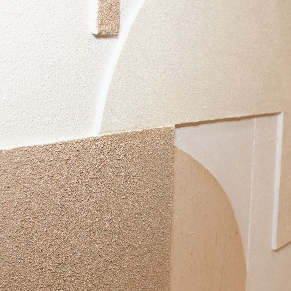 Detalle de cuadro abstracto con relieves y formas geométricas en tonos beige y blanco