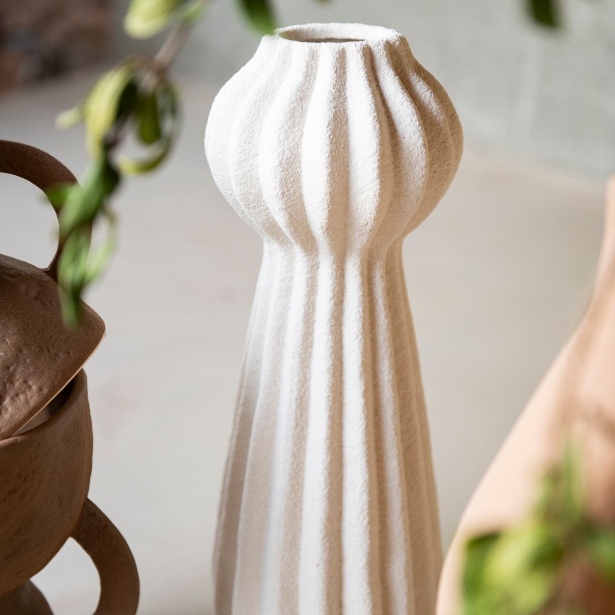 Detalle de jarrón blanco texturizado con diseño acanalado y forma escultórica