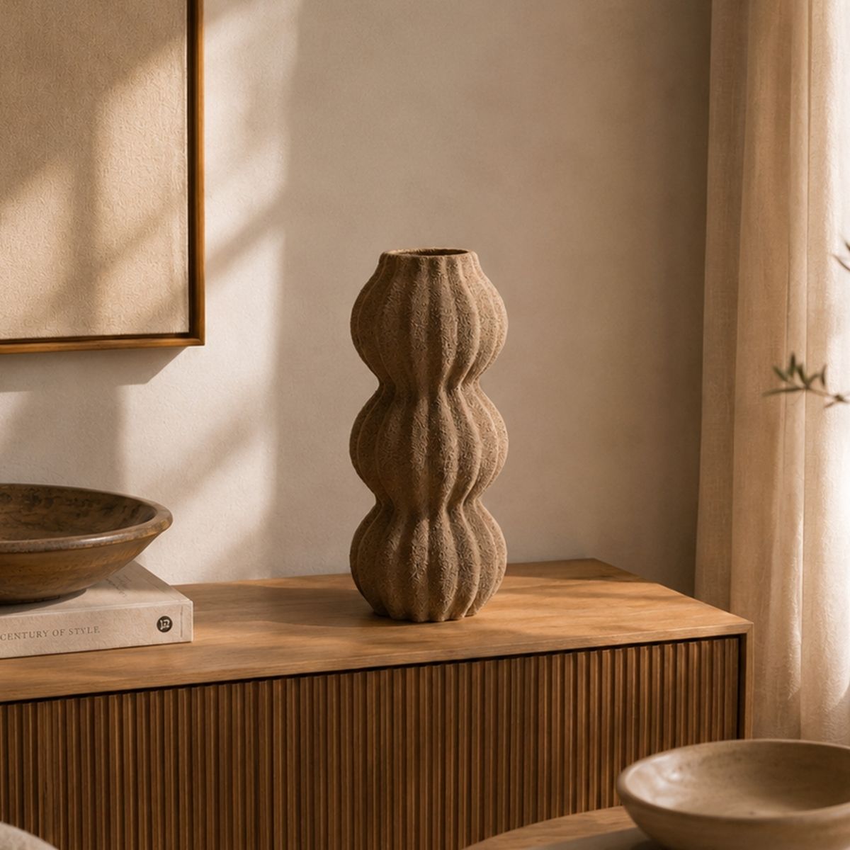 Jarrón decorativo marrón de acabado texturizado y diseño ondulado sobre aparador de madera en ambiente cálido