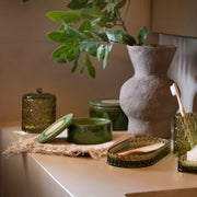 Bote con tapa de vidrio verde Pear en composición de accesorios de baño, Andrea House