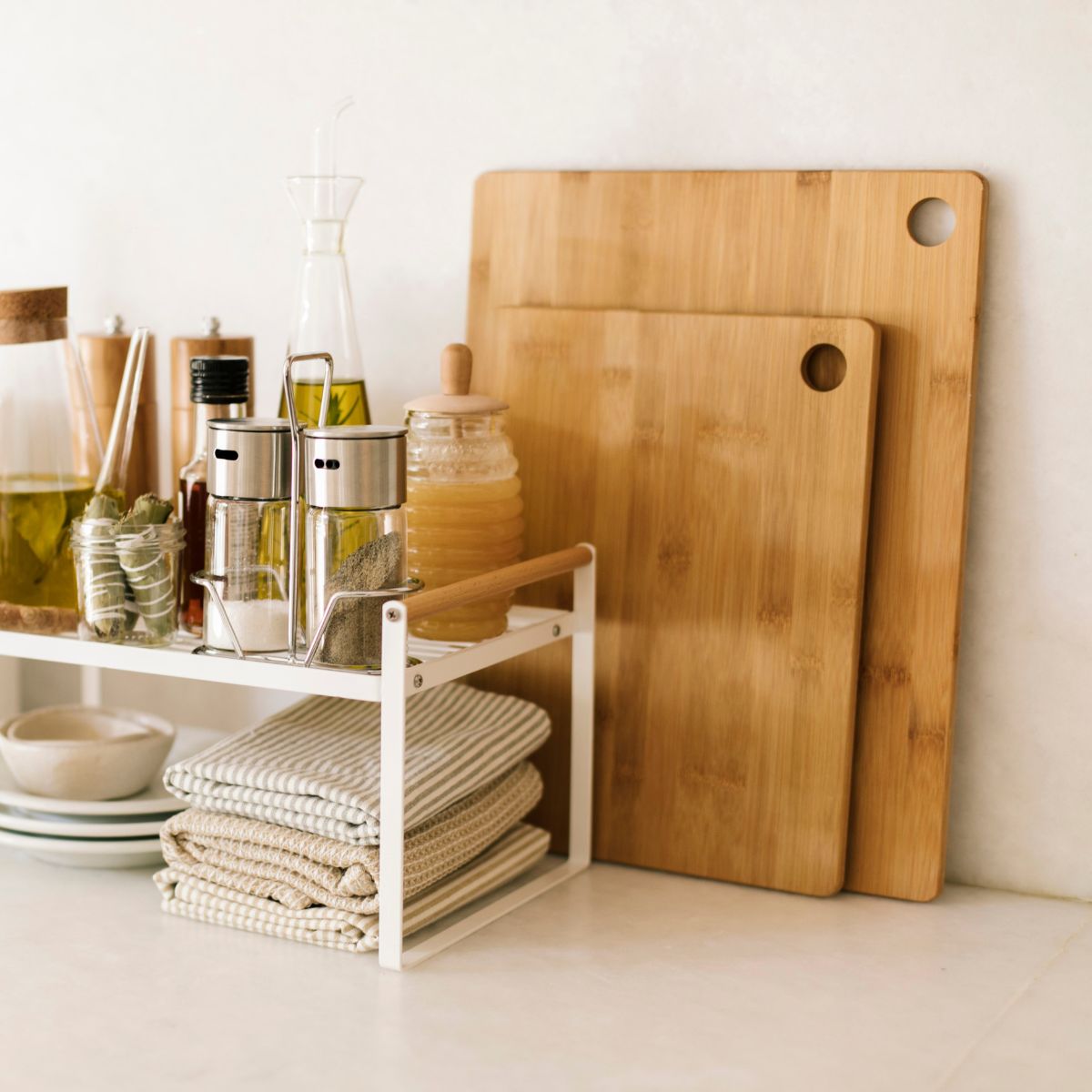 Tablas de cortar de bambú en cocina junto a organizador con especias, aceite y textiles, estilo natural y orden funcional
