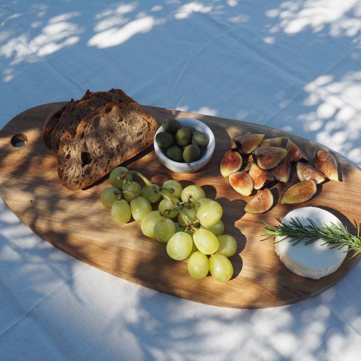 Tabla de cortar de acacia con alimentos para servir al aire libre