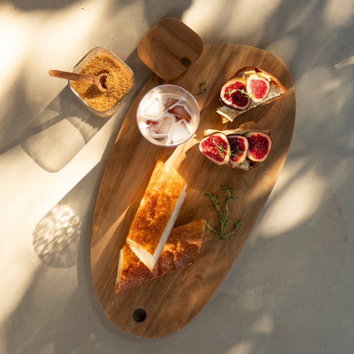 Tabla de madera de acacia con pan y aperitivos para servir