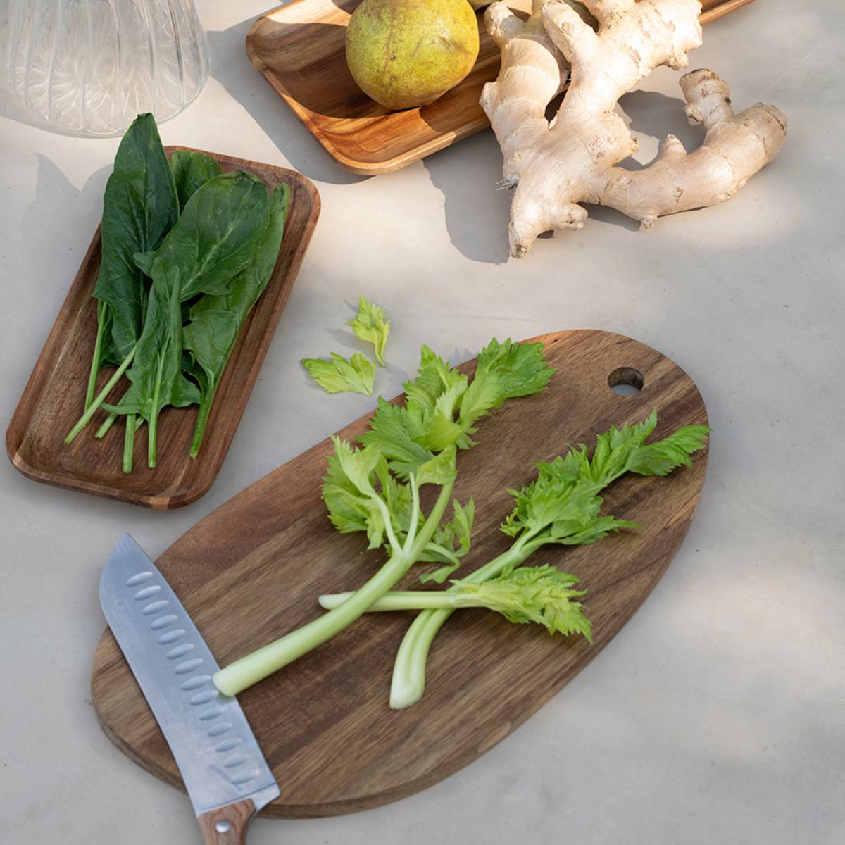 Tabla de cortar de acacia con verduras y cuchillo en cocina