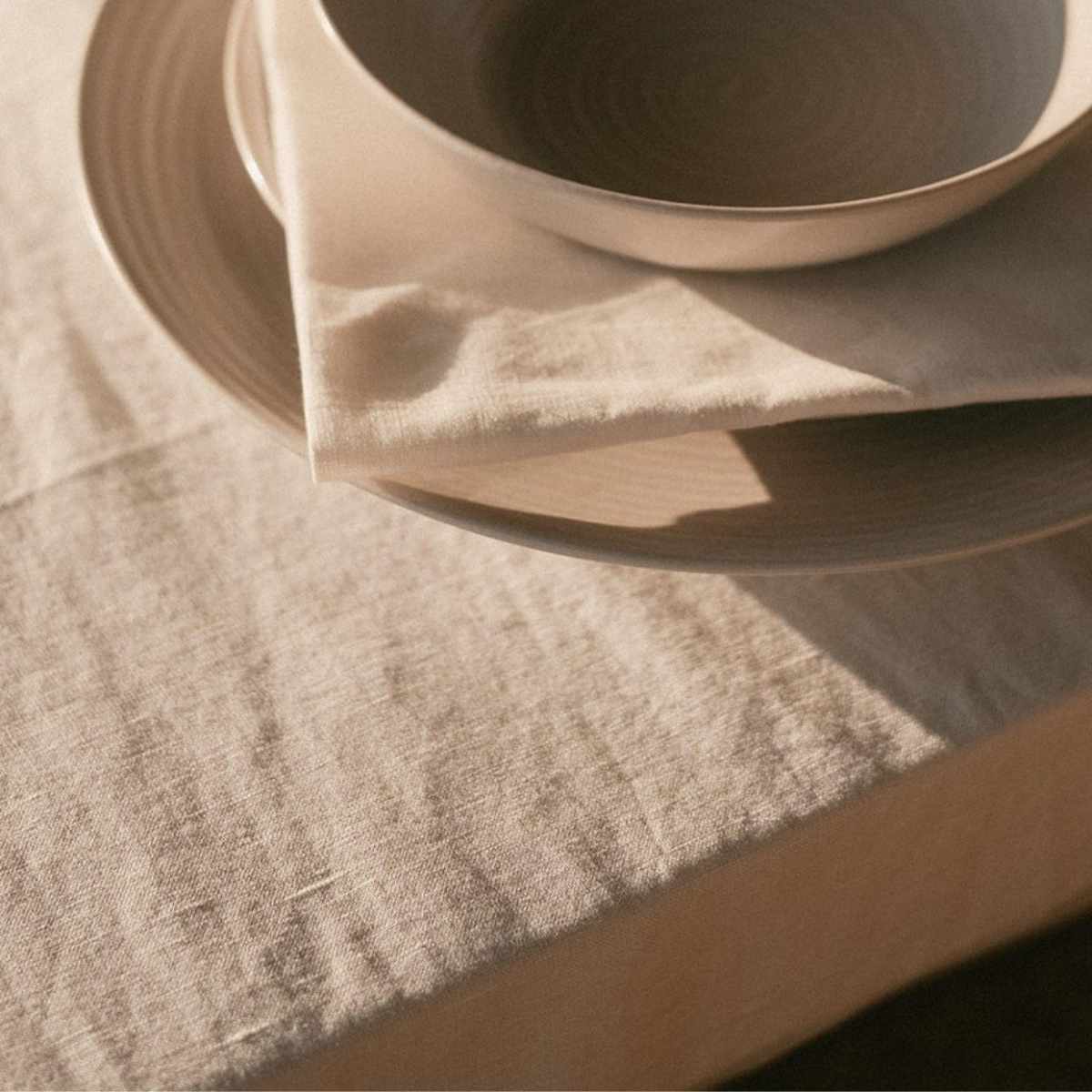 Mesa con mantel de lino beige y platos beige