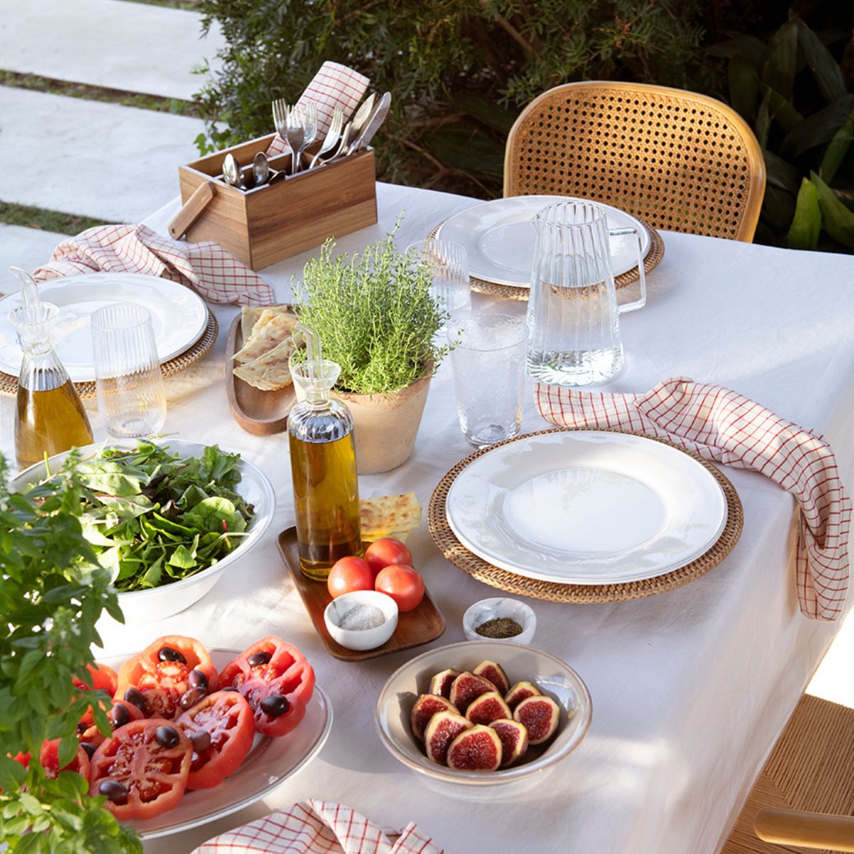 Bajoplato de ratán en mesa de jardín con aceiteras para ensaladas en ambiente veraniego y mediterráneo 
