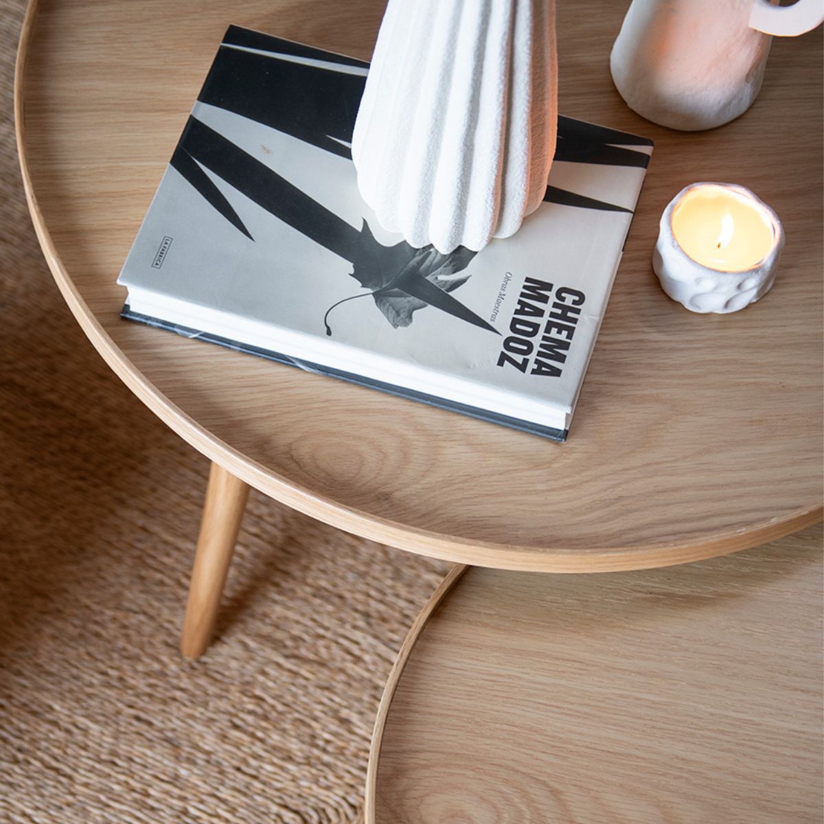 Mesa auxiliar redonda de roble con tablero de madera natural y detalle decorativo.