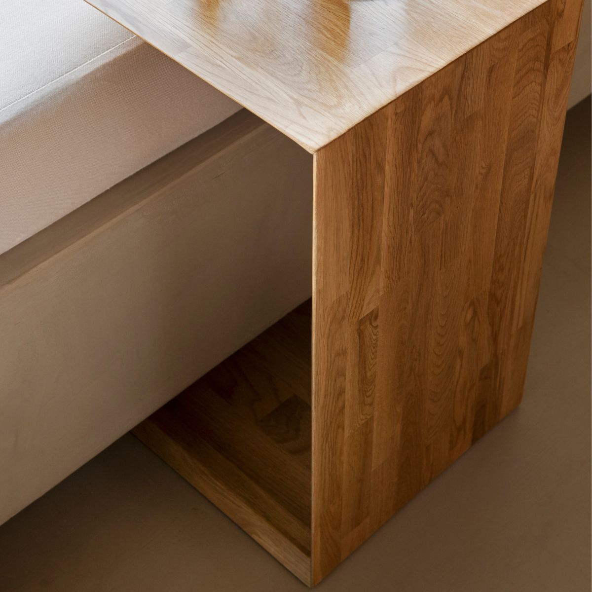 Mesa auxiliar de roble para sofá con diseño funcional y detalle de estructura lateral.
