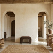 Taburete tapizado marrón de diseño curvo en salón de estilo mediterráneo