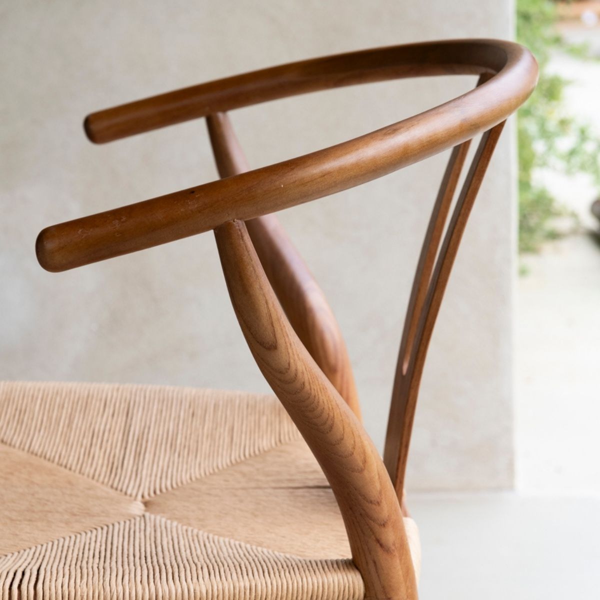 Detalle de silla de comedor de madera con respaldo curvo y asiento de fibra trenzada